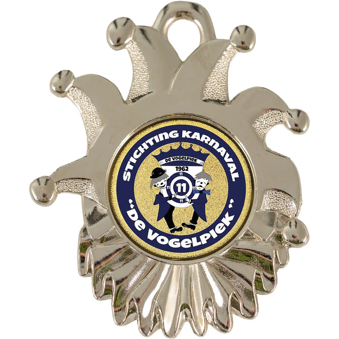 Close-up van medaille Velika zilverkleurig met logo van Stichting Carnaval De Vogelpiek met blauw-wit halslint.